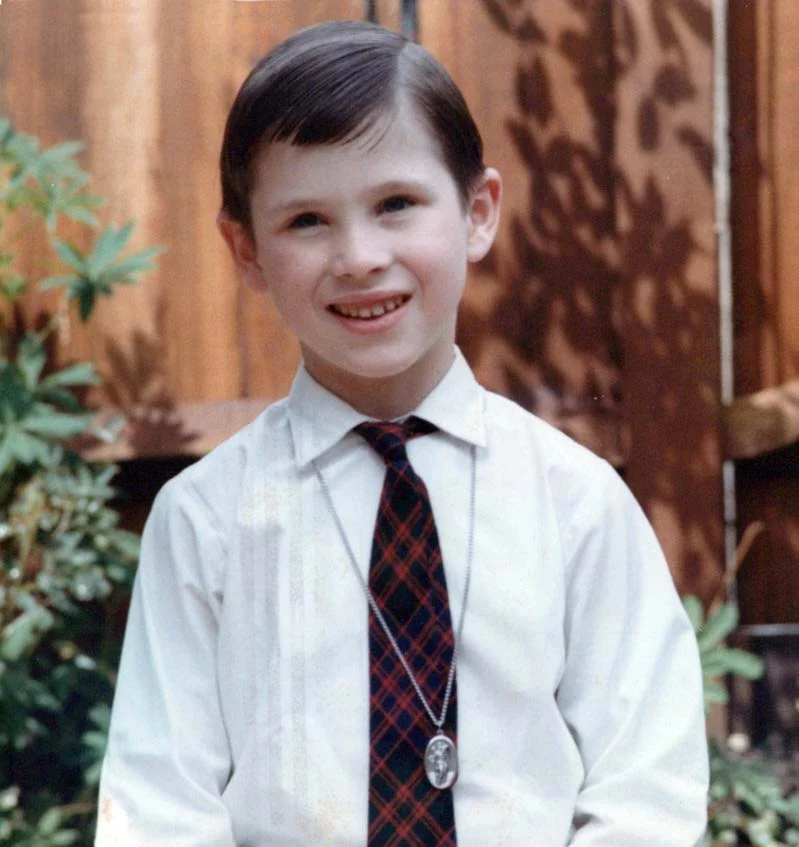 A smiling boy in a white shirt and tie
