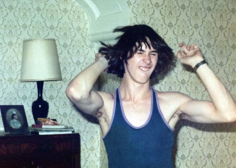 A young man in a vest flexing his arms