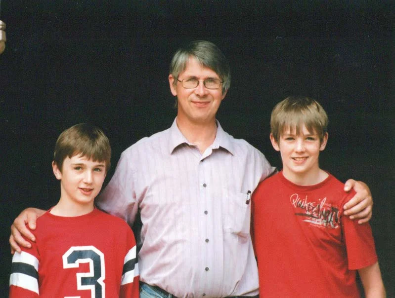 John Murphy standing between two boys in red football shirts