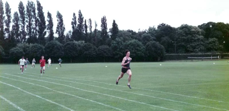 A runner well ahead of the field on a grass running track