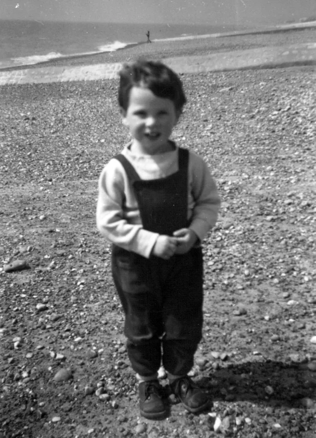 A toddler standing on a pebble beach
